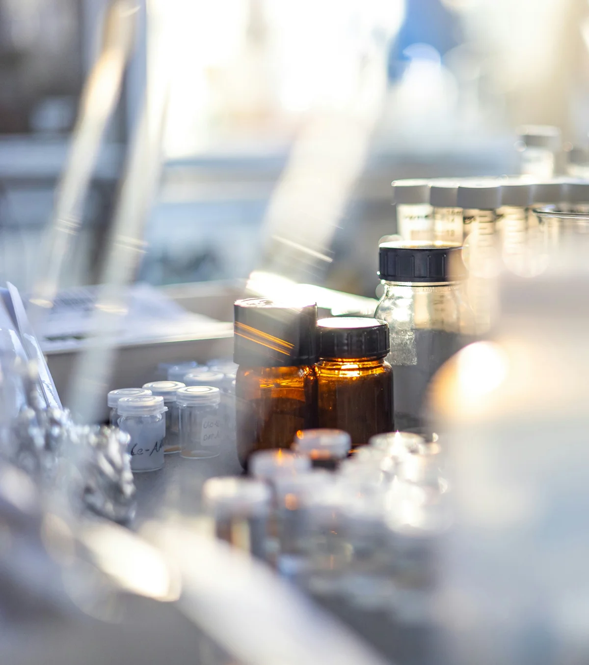 Bancone da laboratorio con diversi flaconi in vetro scuro e piccoli contenitori traspiranti etichettati